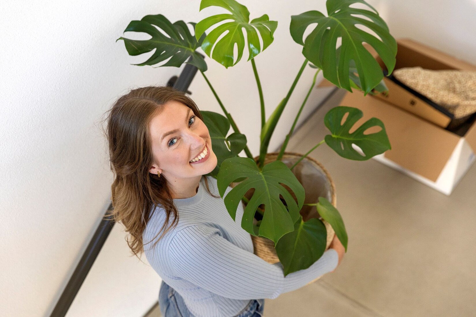 Thuispoort | vrouw loopt trap op met plant in de handen